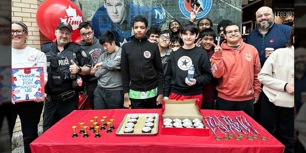 Photo of St. Oscar Romero ISP students, staff, Tim Hortons owner, police officer and more with the donuts, trophies and medals