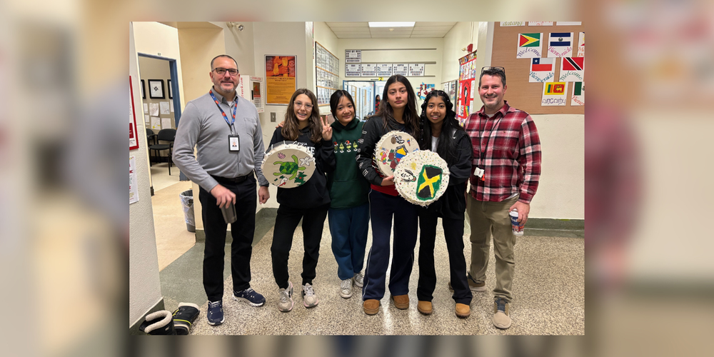 4 students and 2 faculty posing in the school hallway with artwork.