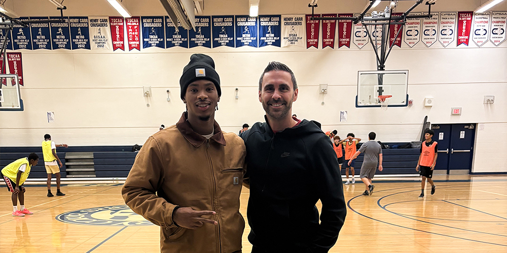 Photo of Kimani with coach in the Father Henry Carr gymnasium