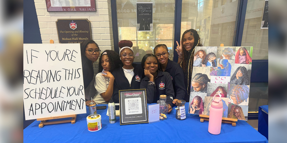 Students at a table offering braid services.