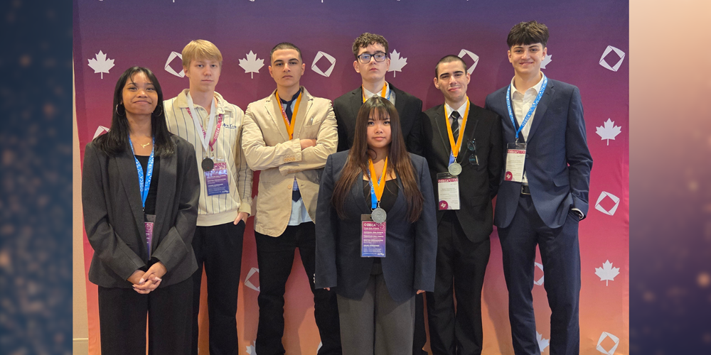 7 students posing dressed up in business attire, and with medals around their necks. 