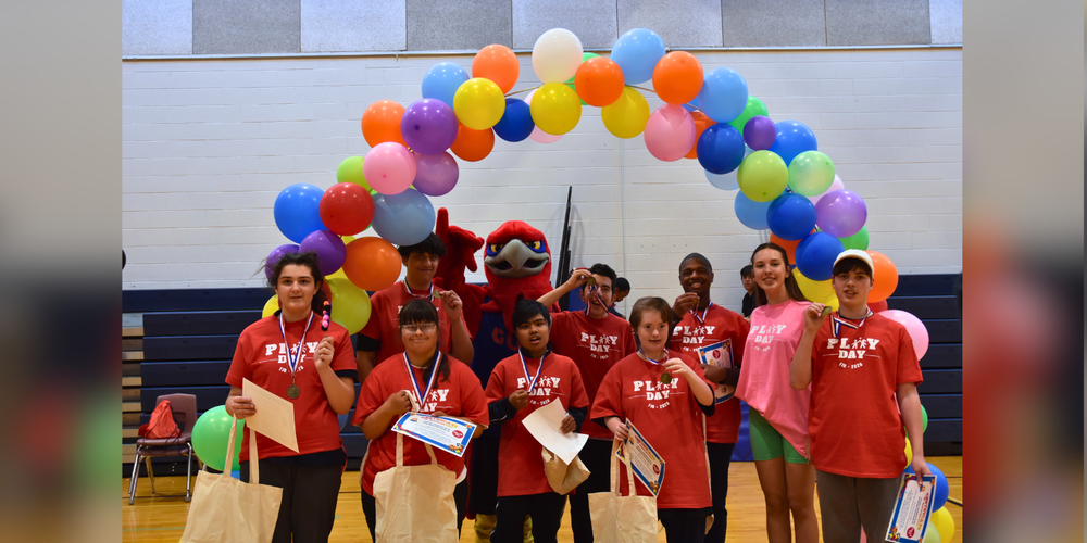 Students posing under a balloon arch.