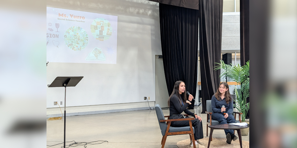 Two women sitting on chairs discussing something in front of a projector. 