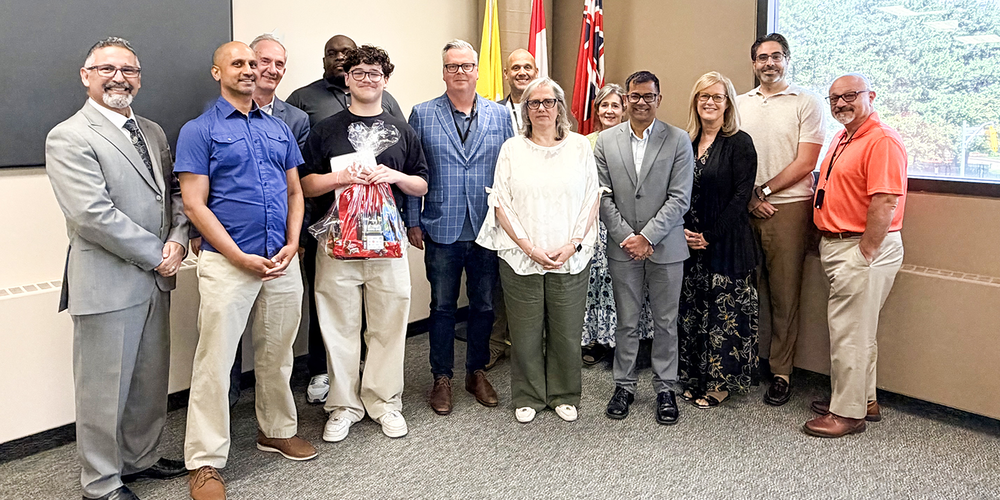 Photo of Ruben with his gift package, posing with CEO Brendan Browne and other TCDSB senior staff