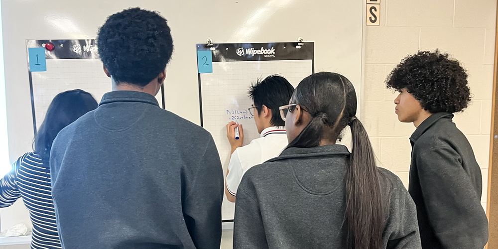 Photo of students working on math sums together on the board