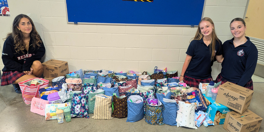 3 students posing with bags full of menstrual products.