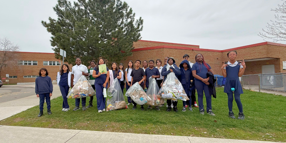 Students posing outdoors with trash bags. 