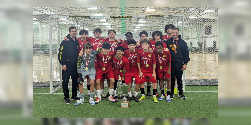 Soccer team posing on an indoor field with coaches.