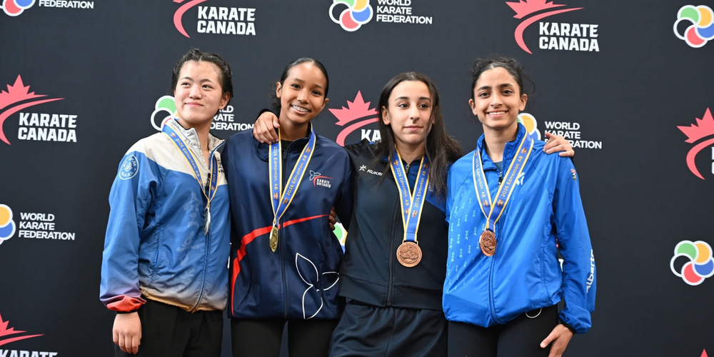 4 students posing with medals around their necks.