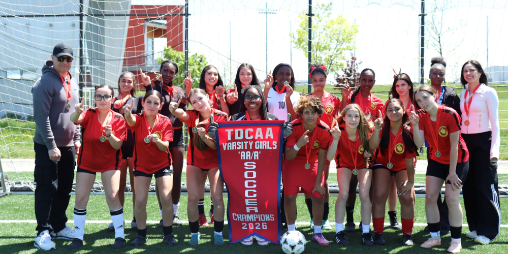 group of soccer team posing outside with champions award