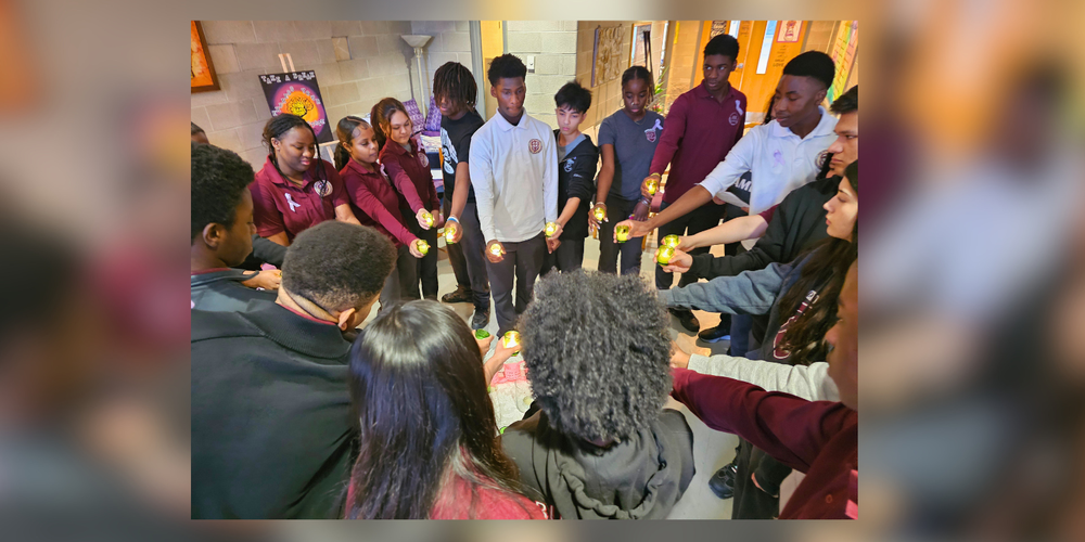 A group of students standing in a circle holding candles.