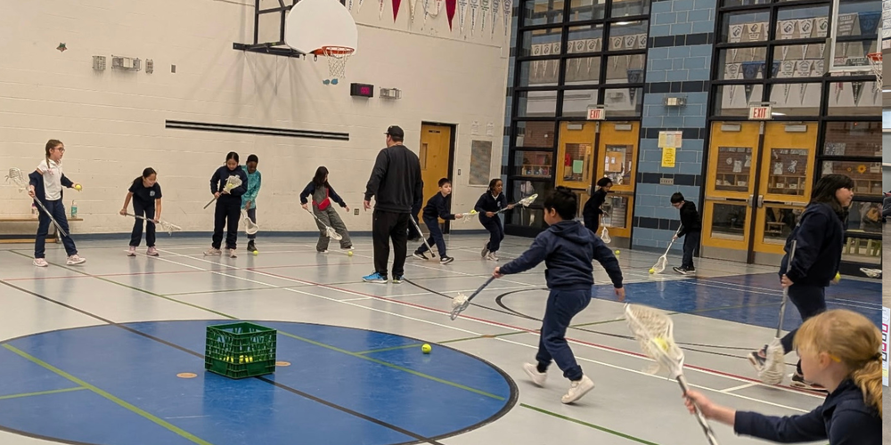 Kids playing lacrosse in a gym