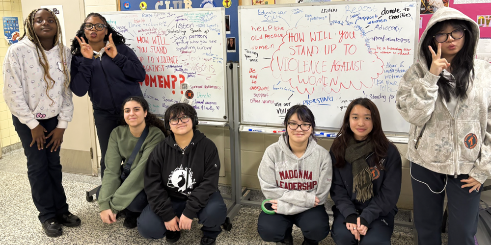 Group photo of Madonna students in front of the displays they created