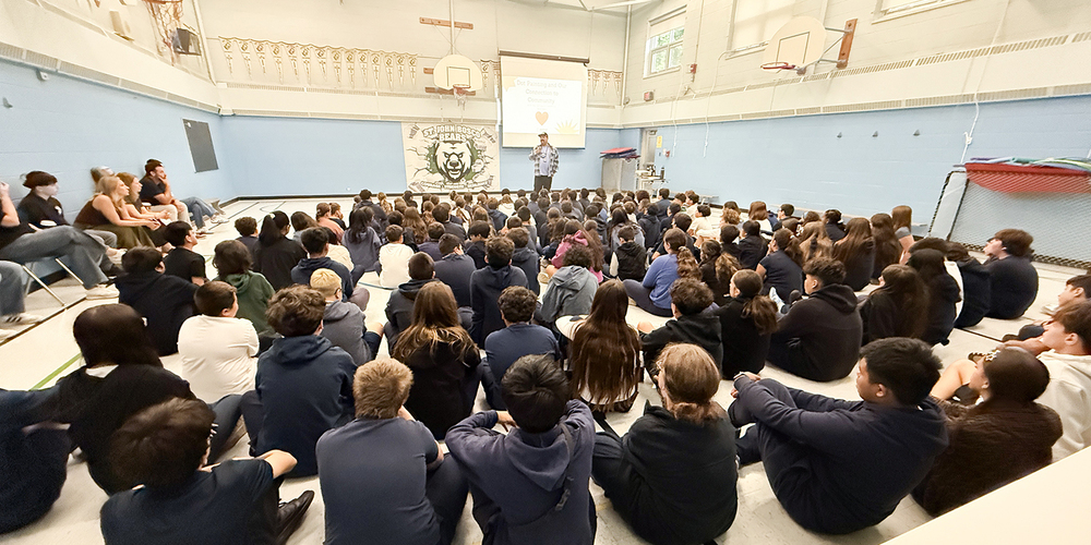 Photo of St. John Bosco students listening to Jason speak during the visit