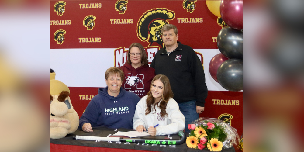Student signing something in front of Trojans backdrop