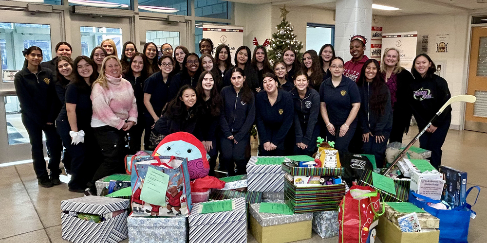 Group photo of Loretto students and staff in front of the Christmas tree, along with the boxes of items collected