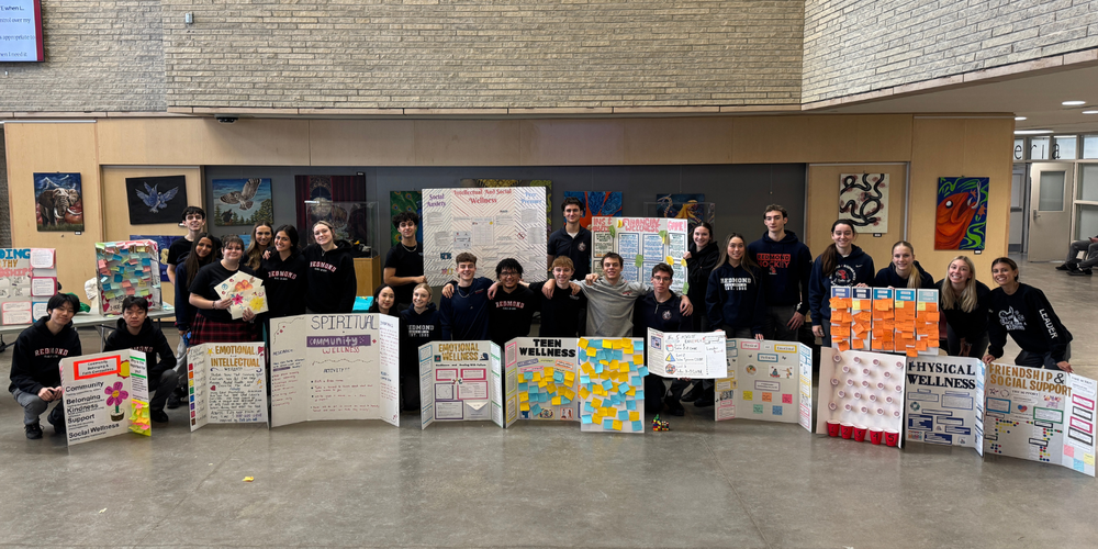 A large group photo of students holding presentation boards.