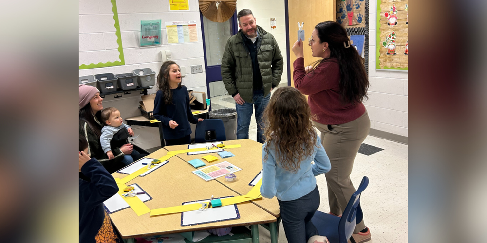 Adults and children participating in an activity in a classroom.