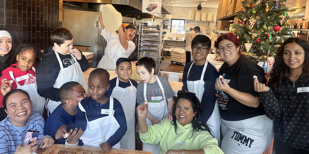 Group photo of Santa Maria students and staff making pizza with North of Brooklyn Pizzeria staff