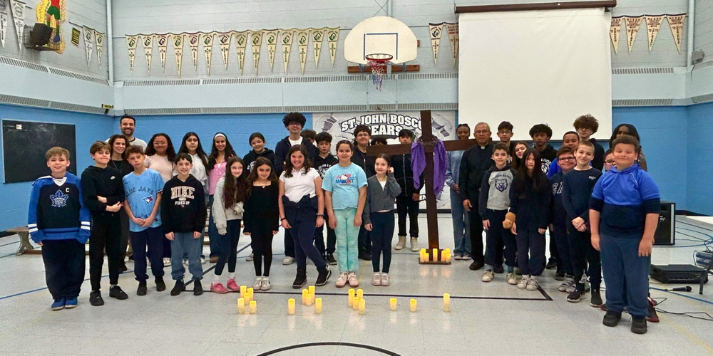 Group photo of young students in a gym with candles on the floor.
