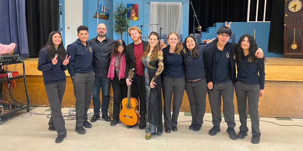 Group photo of students and faculty in a music room with a guitar