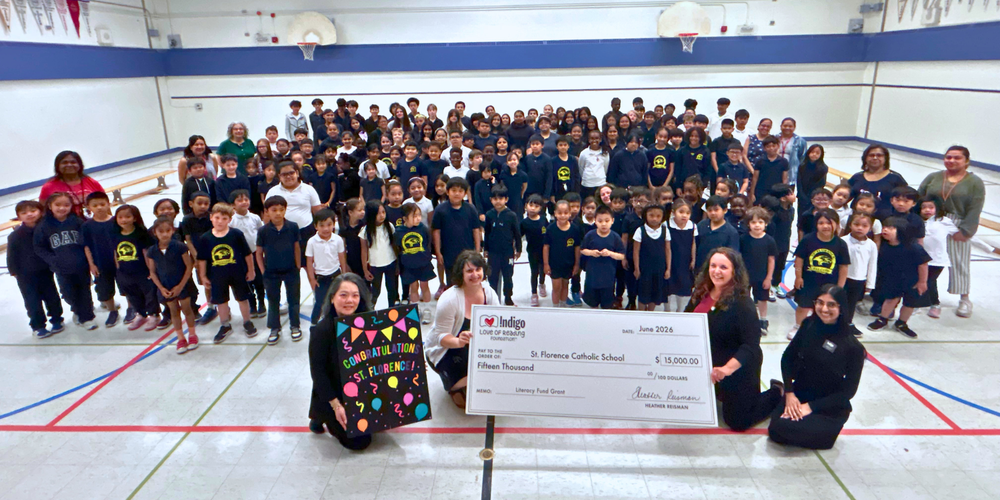 Large group photo in a gym of people holding a giant cheque.
