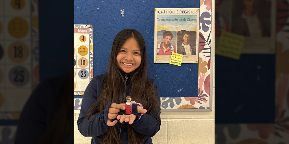 Photo of a student holding up a figurine of a saintly figure