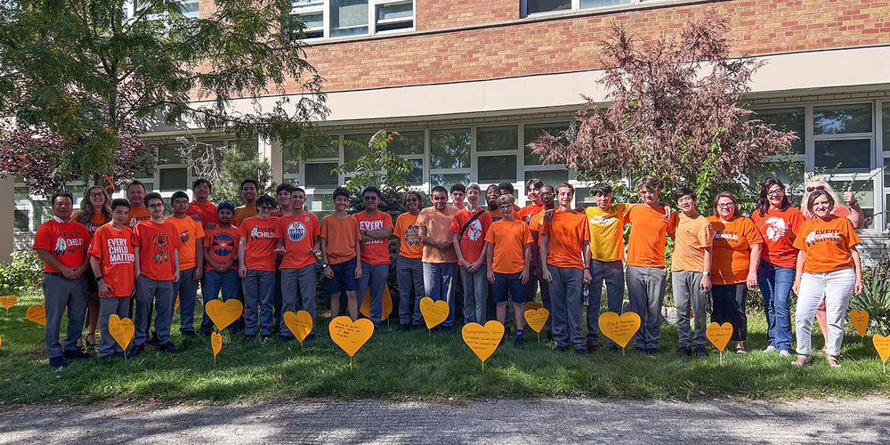 Group photo of Chaminade College School students and staff standing together in their orange shirts
