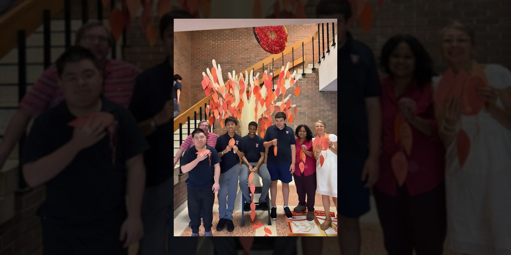 Group photo of SJHN students and staff in front of the tree holding their leaves