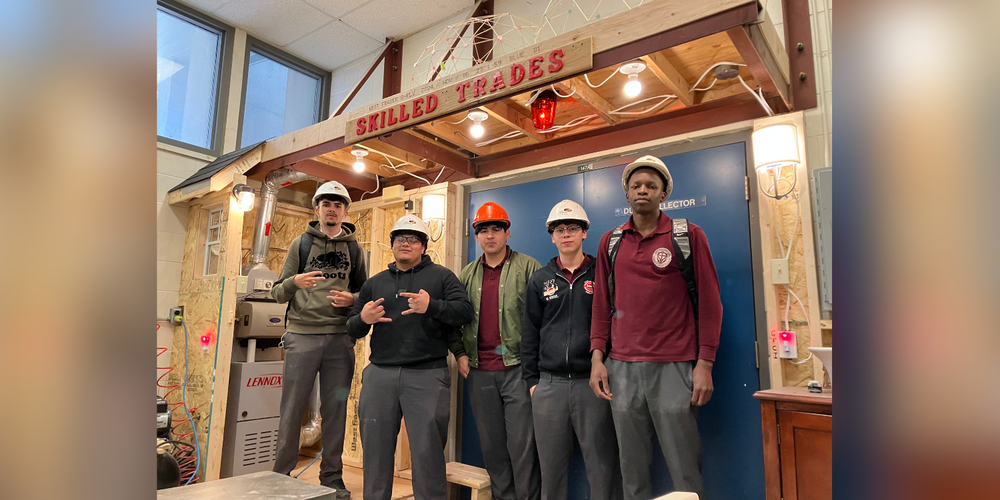 5 students in hard helmets under "Skilled Trades" display