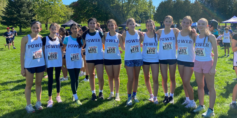 A group of students posing with "POWER" jersey's outdoors.