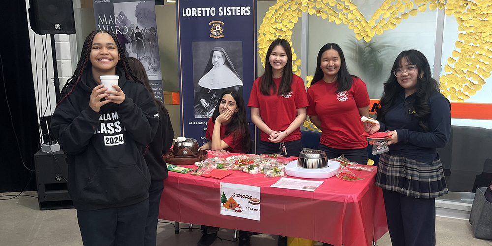 Photo of Loretto College students in charge of a s'mores table