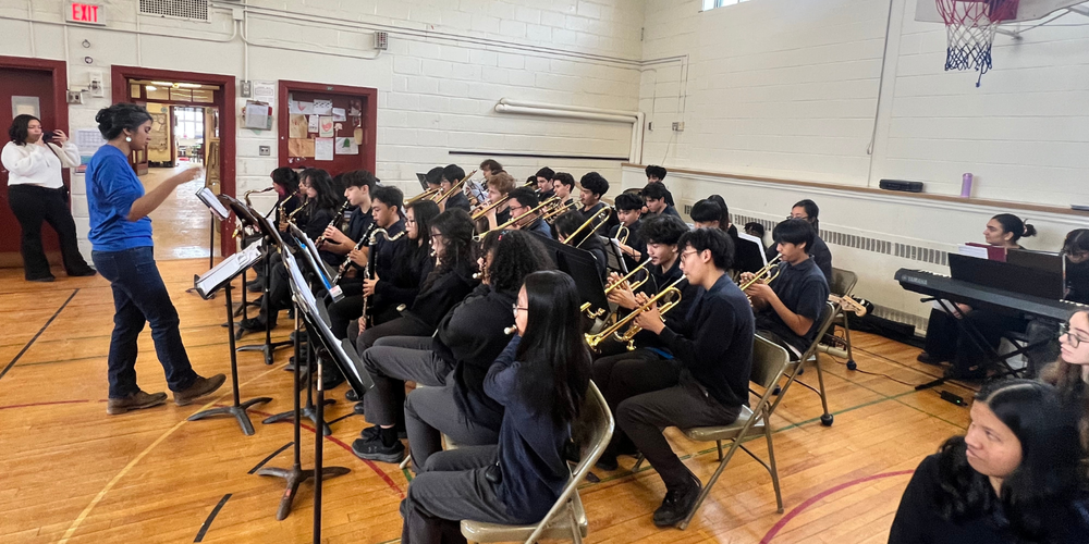 A school band playing instruments with the teacher in front
