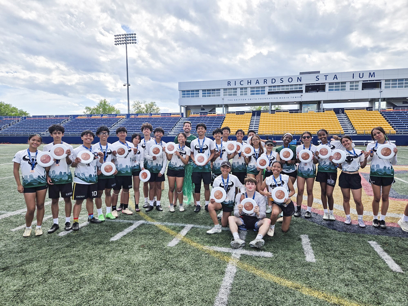 Group photo of the Rebels team on the field wearing their medals and holding frisbees