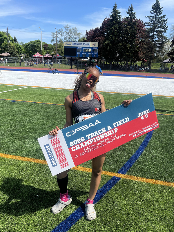 Photo of JCM athlete on the field holding up OFSAA ticket