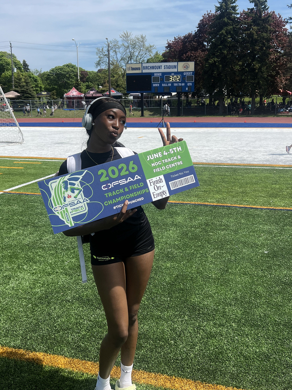 Photo of JCM athlete on the field holding up OFSAA ticket