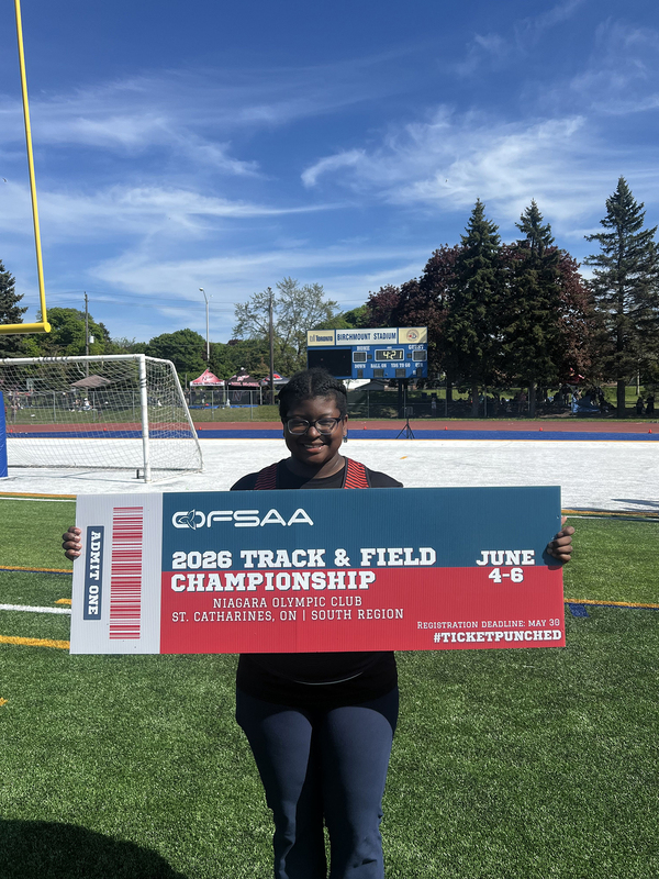 Photo of JCM athlete on the field holding up OFSAA ticket