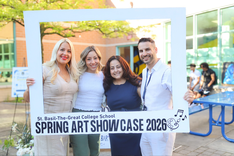 Photo of staff posting together with a large frame that says St. Basil-the-Great College School Spring Art Showcase 2026