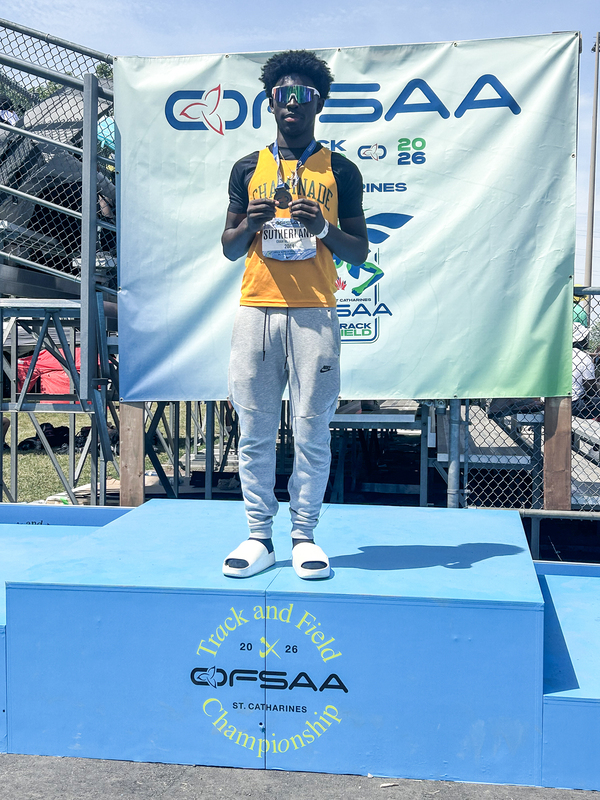 Photo of Jayden on the podium holding his gold medal and wearing his yellow Chaminade jersey