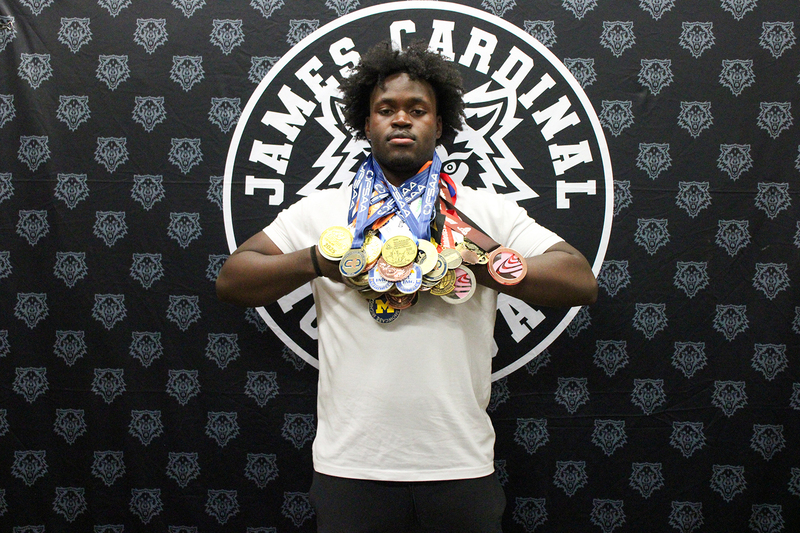 Eghosa at the signing posing with all his medals around his neck at once