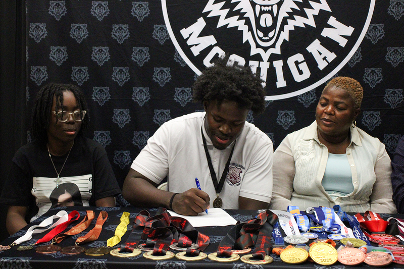 Eghosa at the signing with his family, with all his medals laid out in front of him