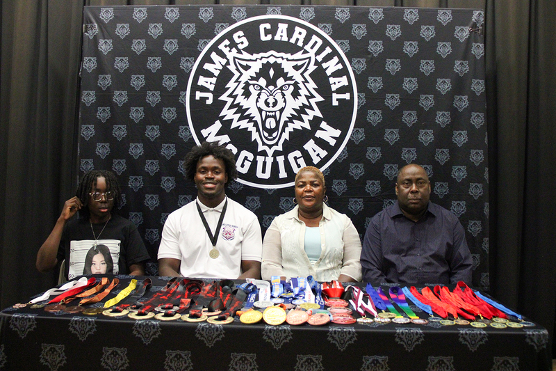 Eghosa at the signing with his family, with all his medals laid out in front of him