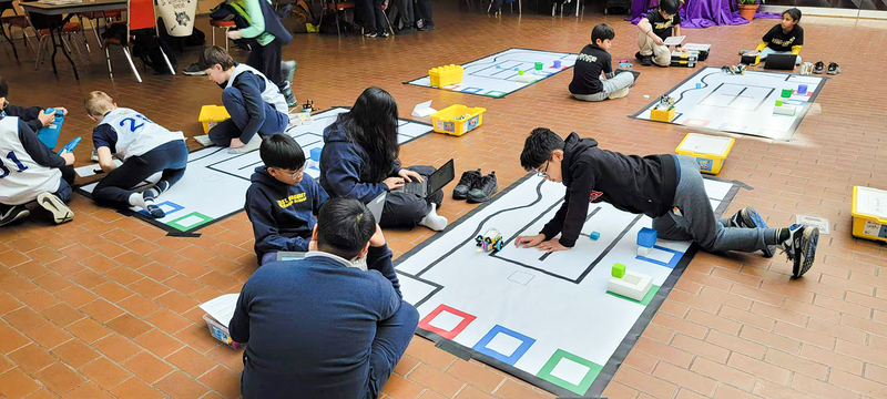 Photo of students working with their robotics during the competition