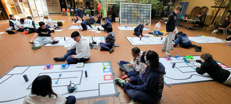 Photo of students working with their robotics during the competition