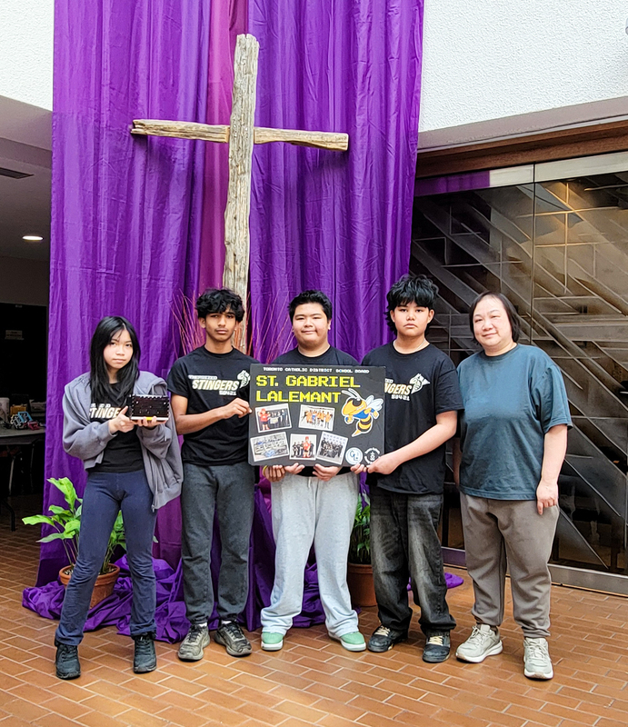 Photo of St. Gabriel Lalemant students holding up their robot and poster board