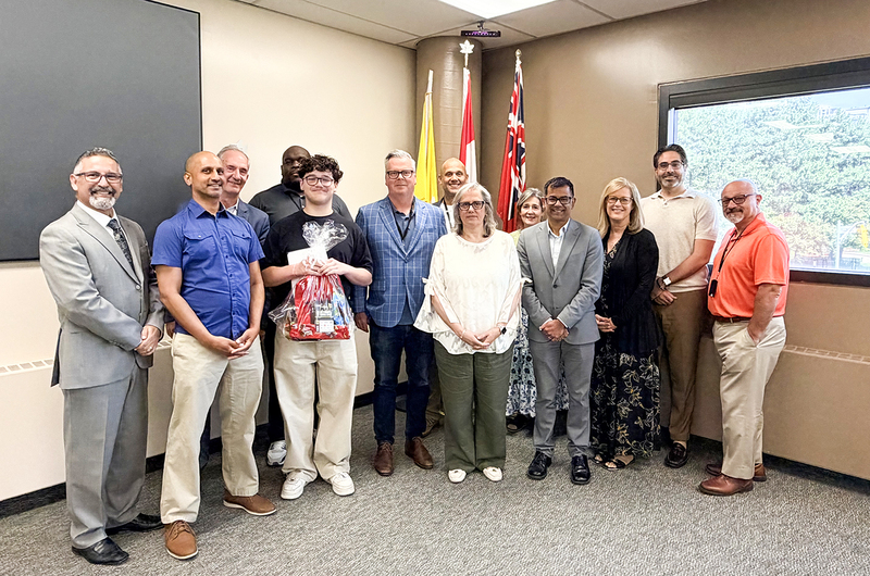 Photo of Ruben with his gift package, posing with CEO Brendan Browne and other TCDSB senior staff