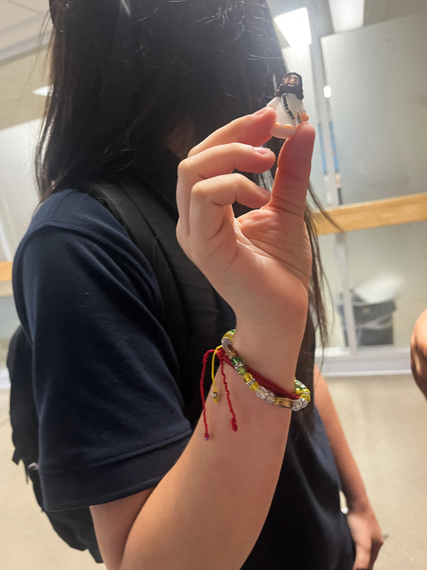 Photo of a Loretto College student holding up the mini figurine of Jesus with the student's face turned away from the camera