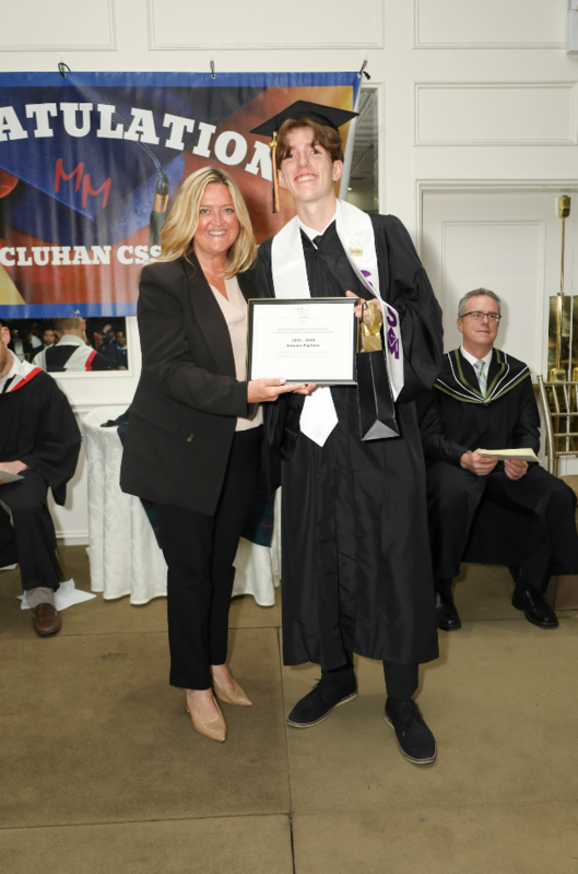 Photo of Antonio getting his framed certificate from Superintendent Shawna Campbell