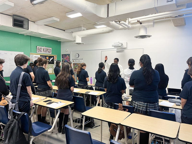 Photo of Father Joseph visiting one of the Loretto College classrooms and the students standing up to listen to him