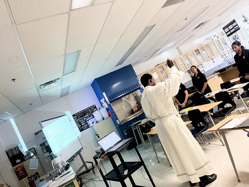 Photo of Father Joseph visiting one of the Loretto College classrooms and the students standing up to listen to him